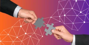Two hands holding puzzle pieces to indicate business collaboration and synergy
