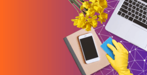 flat lay of someone cleaning a desk with a notebook, phone, computer and daffodils so you know it's spring time